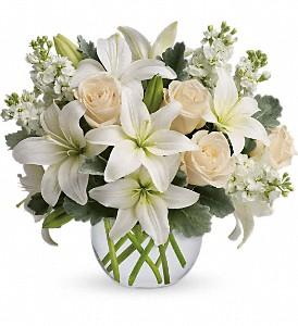 White roses and lily arranged in clear vase make a tasteful bouquet for sympathy flowers. 