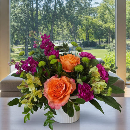 A vibrant fresh flower arrangement in a white ribbed vase, featuring orange roses, magenta alstroemeria, green button chrysanthemums, and yellow-green alstroemeria with free flower delivery in winnipeg