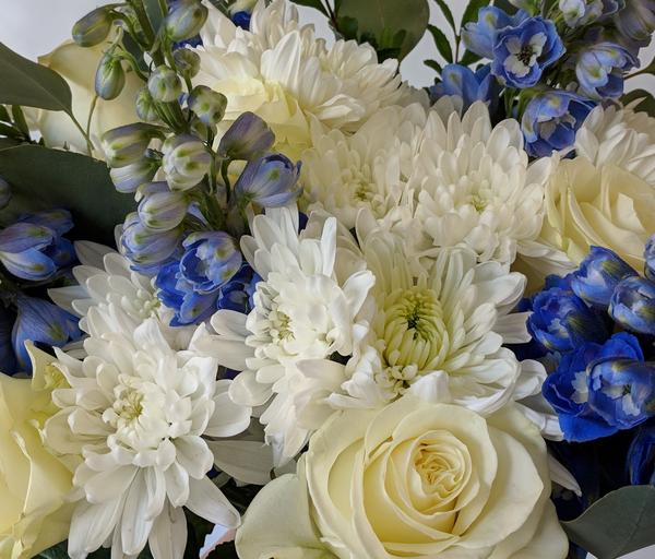 Blue delphinium flowers, white roses with fresh white flowers in handtied bouquet