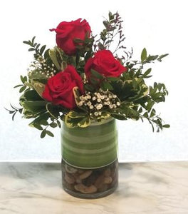 Broadway flowers include roses and greens in simple cylinder vase.